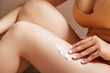 © looking2thesky - Woman applying body cream on her leg in bedroom, closeup. Woman applying body cream on her leg against white background, closeup