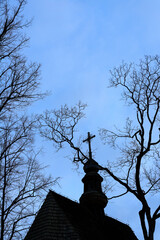 Wall Mural - Silhouette of an old Catholic church among the trees against the blue sky at sunset.