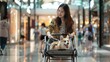 A cheerful woman with a corgi in a dog stroller is walking and smiling in a busy shopping mall corridor.