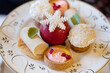 Assortment of bite-sized cakes such as fruit tartlets, cheesecakes, coconut marshmallow balls and a red chocolate sphere decorated with a sugar snowflake, elegant dessert served with teas or coffees