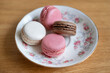 Four delicate macaroons placed on a porcelain plate, confectionery popular for the light texture, selection of fruity flavors and guilty-free petite size, elegant dessert for parties or gatherings