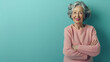 Happy confident attractive senior woman with blue eyes and a wide beaming smile standing with folded arms against a blue background with copyspace