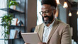 © HillTract - Modern african american businessman holding digital tablet in office space