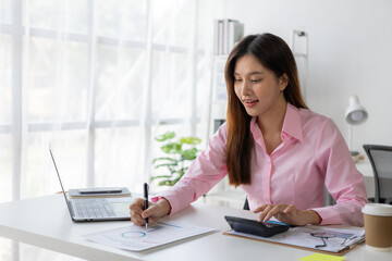 Annual summary report, laptop and paper placed at desk, Asian woman working online and planning financial data with laptop and succeeding with excited and happy face