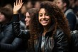 © Vilaysack - A cheerful young woman with curly hair raising her hand to participate during a lecture in a classroom setting, showcasing active engagement and a positive attitude