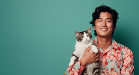 asian man holding cat isolated on plain green studio background with empty copy text space