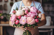 Young woman make a peony bouquet on floral shop, florist workplace