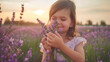A little girl holds sprigs of blooming lavender and inhales their fragrance on a summer evening
