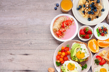 Wall Mural - Healthy breakfast or brunch side border on a wood background. Top view. Avocado toast, smoothie bowls, oats, yogurt and a collection of nutritious foods.