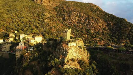 Wall Mural - A Genoese tower above the village of Nonza in the middle of the arid and green mountains, in Europe, in France, in Corsica, towards Bastia, by the Mediterranean Sea, in summer, during a cloudy day.