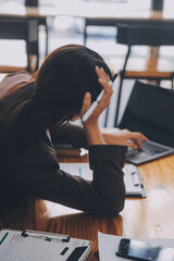 Asian women are stressed while working on laptop, Tired asian businesswoman with headache at office, feeling sick at work, copy space