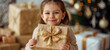 A child tenderly cradles a gift box adorned with a shimmering gold bow