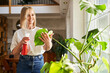 © baranq - Woman sprinkling monstera plant at home