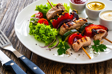 Wall Mural - Meat skewers - grilled meat with vegetables on wooden background
