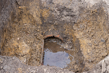 Broken and damaged clay tile in farm field drainage system. Farming flood control, water drainage and agriculture concept.