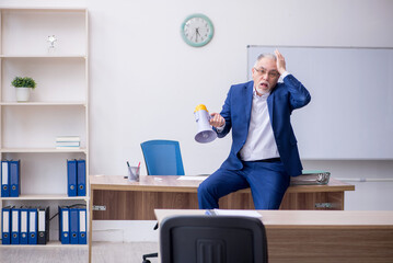 Wall Mural - Old male teacher holding megaphone in the classroom