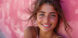Junge hübsche Frau lächelt, Mädchen mit rosa Oberteil vor einer rosa Wand