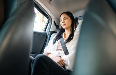 Wall Mural - Relaxing moment of beautiful woman sleeping in car back seats with safety belt. Female happy in car while traveling on the road to destination.