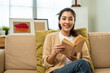 © Chanakon - Asian beautiful woman sitting reading book on cozey couch sofa in living room with sun light morning. People female stay home part time relax at home.