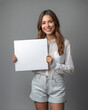 © New generate - Smiling Young woman showing and holding blank white billboard