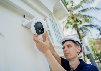 Wall Mural - A technician installs a CCTV camera on the facade of a residential building.