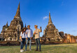Thai local tour guide is explaining the history of old Siam to the couple of tourist on their backpacker honeymoon travel to ancient temple of Ayutthaya, Thailand