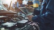 mechanic uses tablet computer to inspect car engine