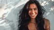 © Z A C - Smiling woman with long dark hair radiant skin and a warm inviting expression standing in soft natural light with a backdrop of a textured wall and dappled shadows.