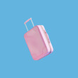 Pink travel suitcase levitate in the air against a blue background. Summer holiday aesthetic vacation idea.