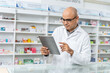 © BJ Day Stock - Happy handsome asian male pharmacist wearing eyeglasses and lab coat working with tablet. He feels good, trustworthy and proud of his work in the pharmacy drugstore.