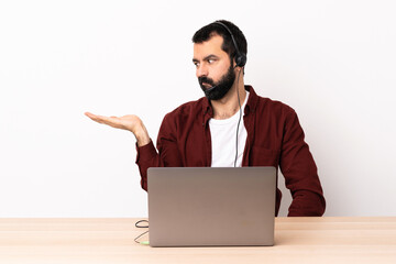 Wall Mural - Telemarketer caucasian man working with a headset and with laptop holding copyspace with doubts.