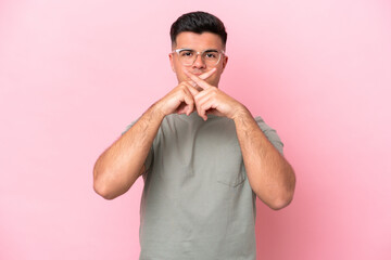 Wall Mural - Young caucasian handsome man isolated on pink background showing a sign of silence gesture