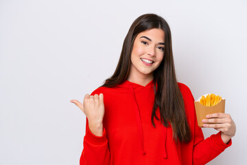 Wall Mural - Young Brazilian woman catching french fries isolated on white background pointing to the side to present a product