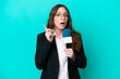 Young TV presenter woman isolated on blue background intending to realizes the solution while lifting a finger up