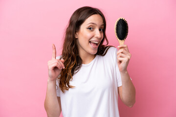 Sticker - Young caucasian woman with hair comb isolated on pink background pointing up a great idea