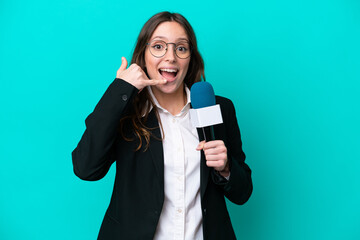 Young TV presenter woman isolated on blue background making phone gesture. Call me back sign