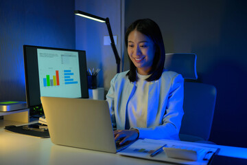 Portrait of young hardworking businesswoman working overtime during the night in her office room.