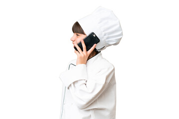 Sticker - Little caucasian chef girl over isolated background keeping a conversation with the mobile phone with someone