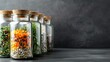 Glass jars with various dried herbs and spices on a dark background with copy space.