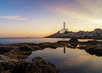 Sticker - landscape view of the Botafoc Lighthouse in Ibiza Town Port at sunsetwith reflections in tidal pools in the foreground