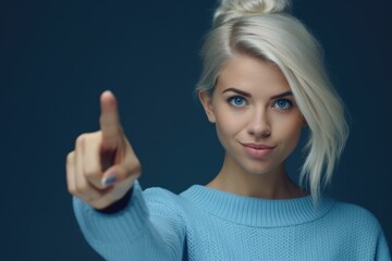 Poster - A woman in a blue sweater pointing at the camera. Suitable for various promotional materials