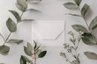 © Alexey - Minimalist envelope mockup with fresh greenery on a clean white surface. Modern flat lay for branding and wedding invitations