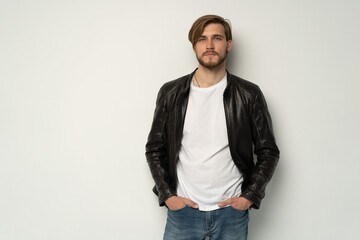 Wall Mural - Handsome young man isolated. Fashionable man in leather jacket is standing on white background