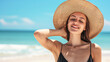© Kowit - Radiant young woman in a swimsuit and sunhat, enjoying the sunshine on a serene beach.