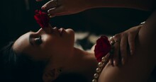 Sensual Woman Touching Face With Red Rose On Bed