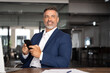 © Stock 4 You - Smiling mature European businessman holding smartphone in office. Middle aged manager using cell phone mobile app, copy space. Digital technology application and solutions for business development.