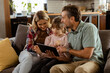 © BGStock72 - Family bonding over a digital tablet in a cozy living room evening