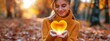 girl holding glow heart shape in hands, embracing positive emotions and wellbeing during fall season