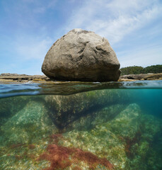 Wall Mural - Granite boulder on the ocean shore, split view half over and under water surface, natural scene, Atlantic coast in Spain, Galicia, Rias Baixas