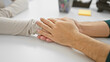 © Krakenimages.com - A man and woman teaming up in a bright office touching hands in a supportive gesture.